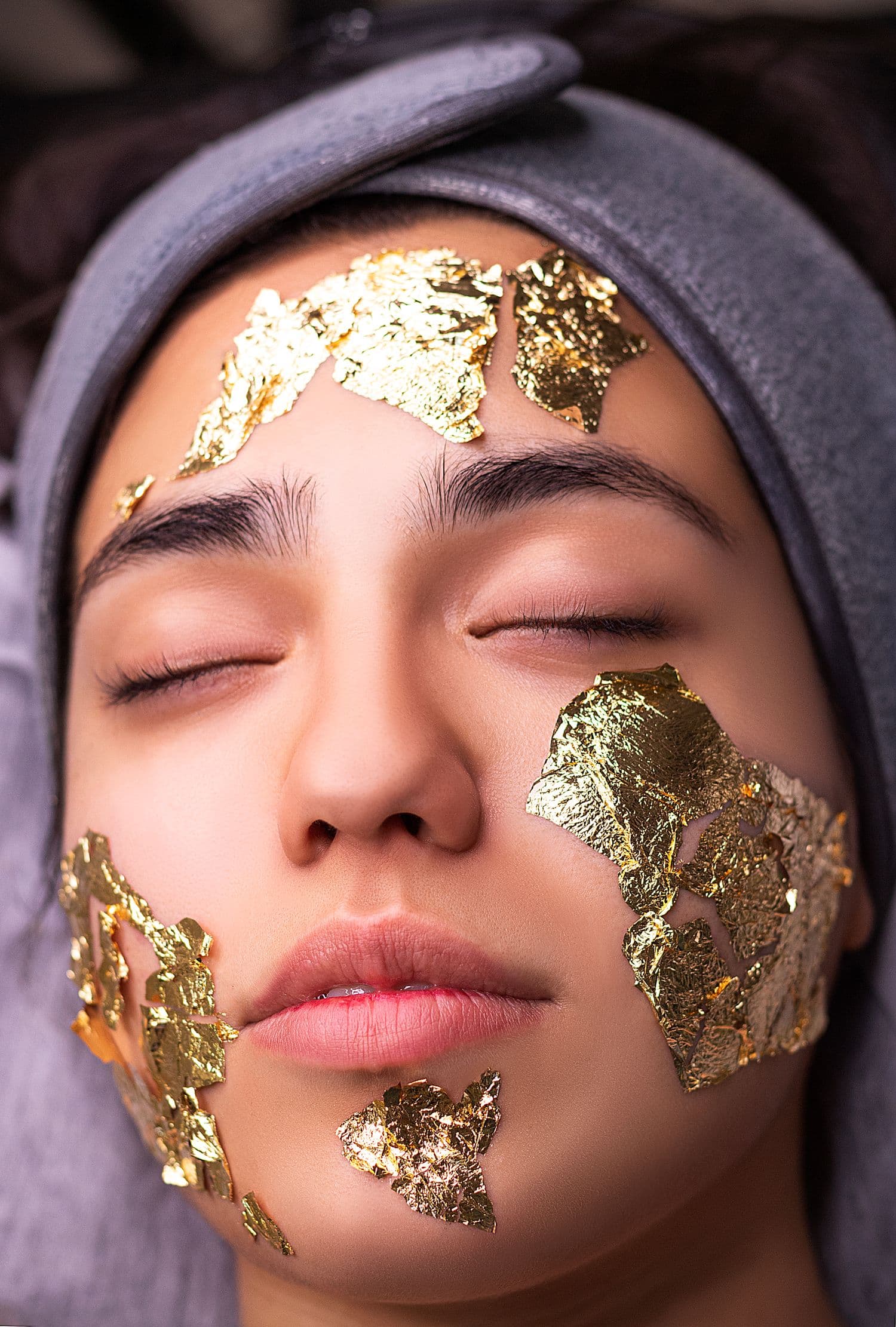 Rostro en reposo con detalle dorado durante un tratamiento facial de estética avanzada